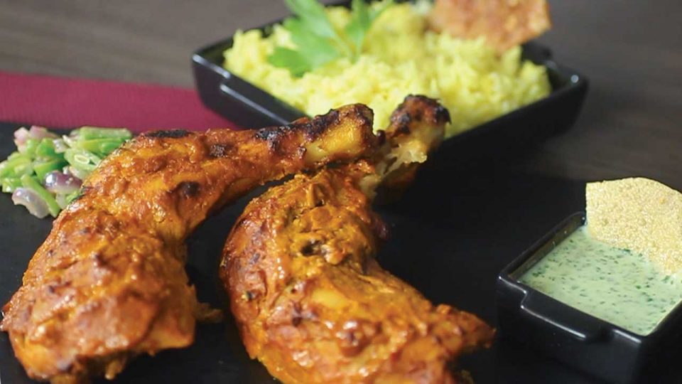 Kip tandoori uit de oven met een yoghurtsaus, gele rijst en sperziebonen